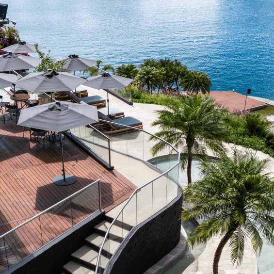 Terraza de Tau House con sombrillas y piscina frente al agua